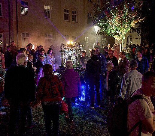 Visitors stand around an illuminated installation.