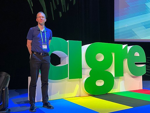 Stefan Kornhuber in front of the cigre display in a presentation hall.