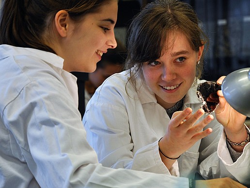 Two girls examine a stone.