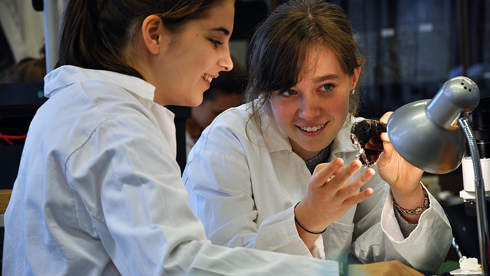 Two girls examine a stone.