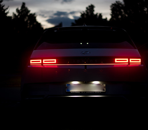 E-Auto von hinten im Dunkeln mit Scheinwerfern