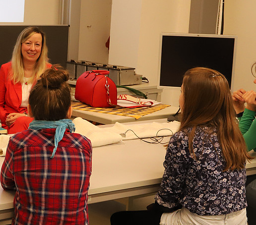 The Vice Principal sits in front of three young girls and smiles at them.