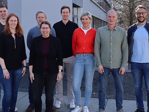 Acht Mitglieder der Nachwuchsforschergruppe „Toolbox Biomedizin“ stehen bei sonnigem Wetter vor einem Hochschulgebäude auf dem Campus der Hochschule Zittau/Görlitz und blicken in die Kamera.