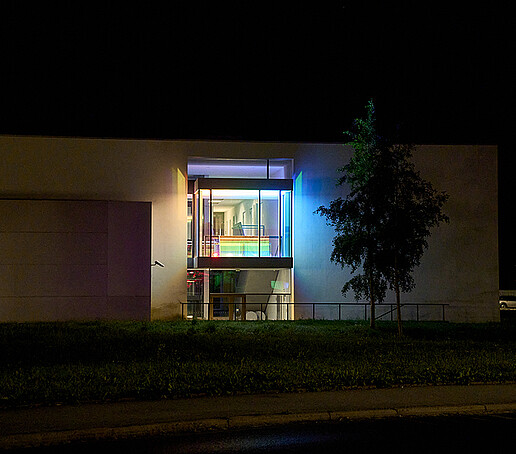 The window of a university building lights up in rainbow colors.