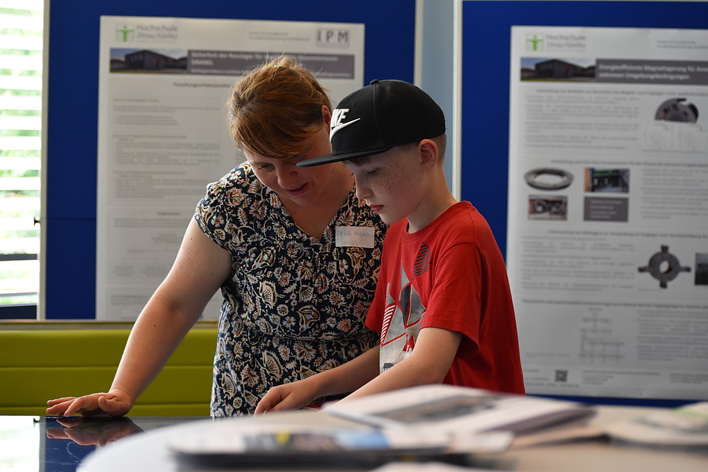 A woman and her young son look at a large wiping table at the stand of the Institute of Process Automation, Process Engineering and Metrology