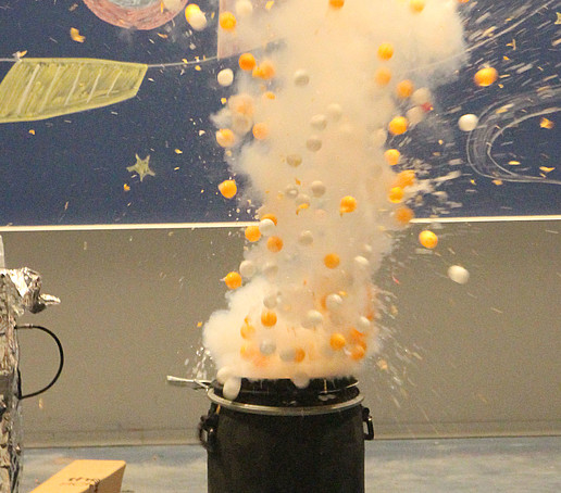Yellow and white balls and steam rise from a barrel.