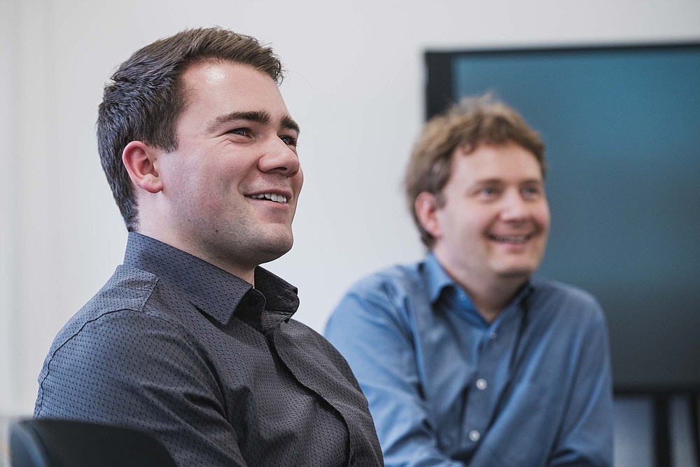 KIA student Richard sits smiling at a table in a conference room.