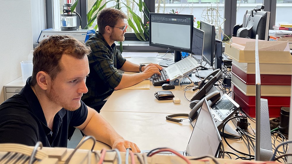 Jan-Hendrik Smith and Karl Jacobie are sitting at their desks working on their computers.