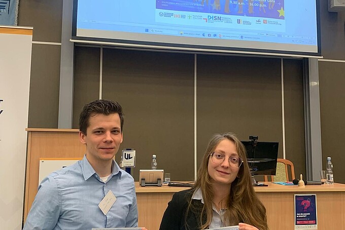 Two young researchers hold a certificate in their hands.