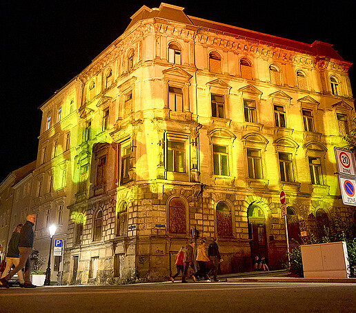 A building on the Zittauer Stadtring is illuminated in yellow.