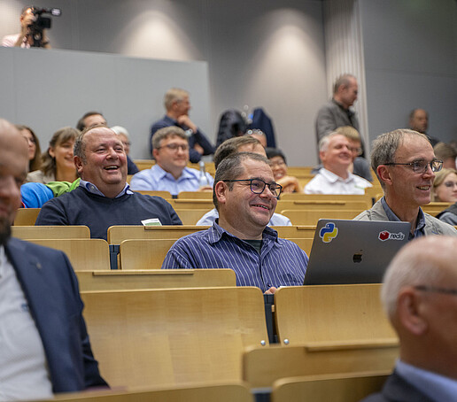 Smiling and laughing guests sit in the audience.