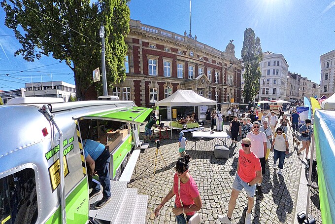 Besucher laufen auf den Mobilen Lernort-Anhänger zu.