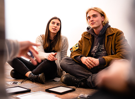 Students sitting on the floor talking.