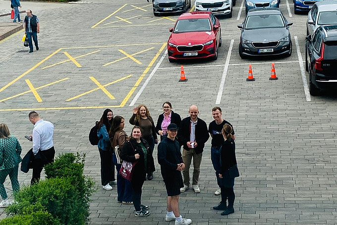 A group of students is standing in a parking lot.