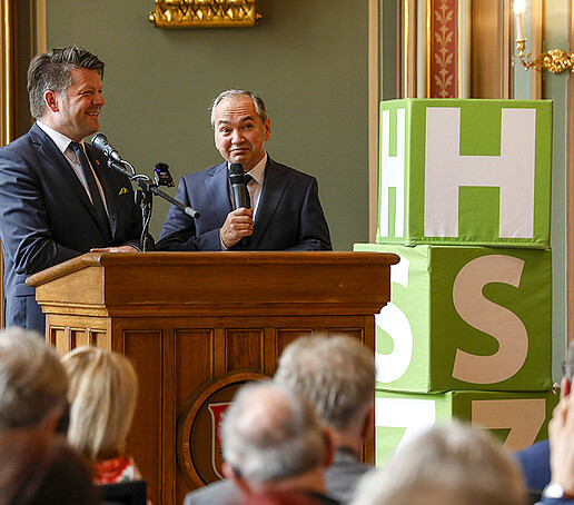 Mr. Zenker and Mr. Ursu stand together at the lectern and address the audience.