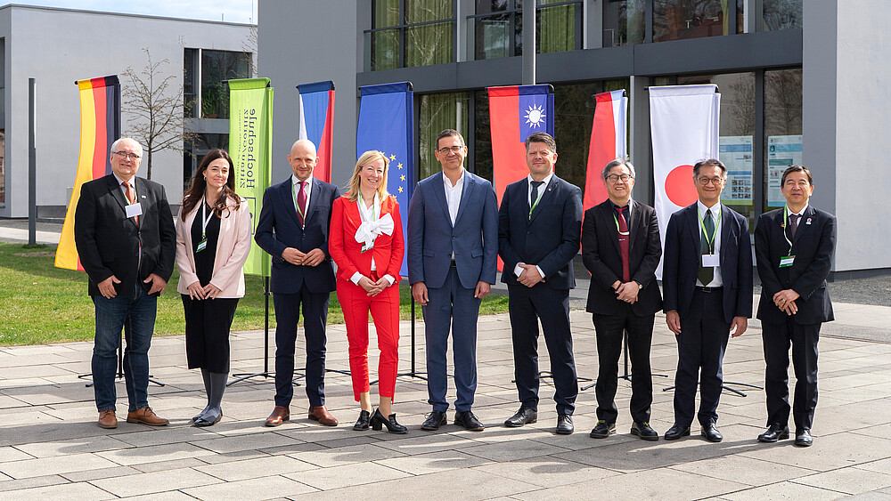Group photo in front of the Zittau/Görlitz University of Applied Sciences building with ten people in front of international flags. Pictured from left to right: Miroslav Brzezina, Kateřina Maršíková, Stephan Meyer, Sophia Keil, Christian Koitzsch, Thomas Zenker, Jhy-Wey Shieh, Lian-Ruey Ke, Kunihiko Kawazu.