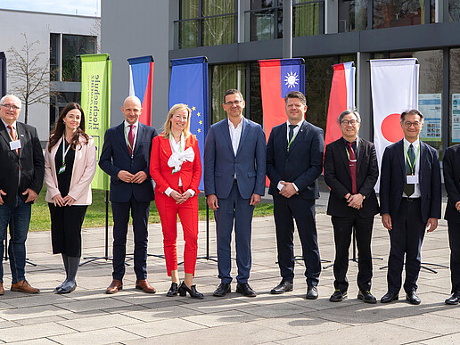 Group photo in front of the Zittau/Görlitz University of Applied Sciences building with ten people in front of international flags. Pictured from left to right: Miroslav Brzezina, Kateřina Maršíková, Stephan Meyer, Sophia Keil, Christian Koitzsch, Thomas Zenker, Jhy-Wey Shieh, Lian-Ruey Ke, Kunihiko Kawazu.