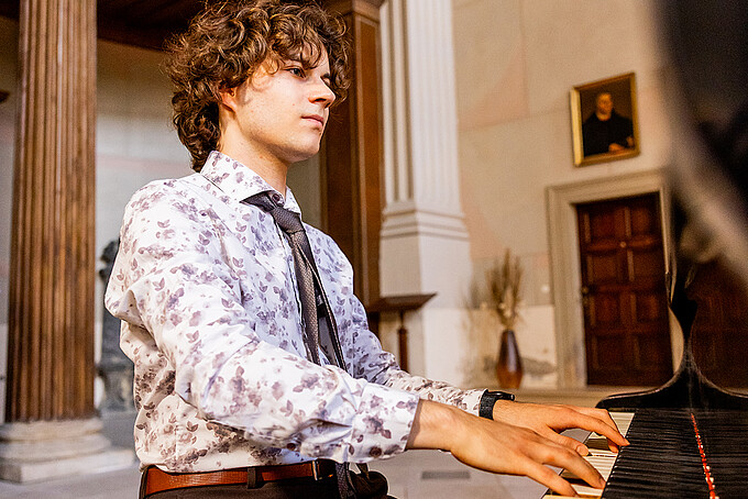 Jonathan Zopf is sitting at the grand piano and playing during the enrollment ceremony.