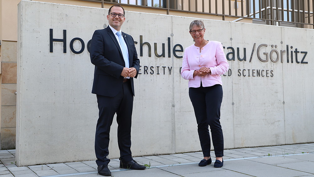 Der Rektor Professor Alexander Kratzsch und die Staatssekretärin Andrea Franke stehen vor dem Schriftzug "Hochschule Zittau/Görlitz"