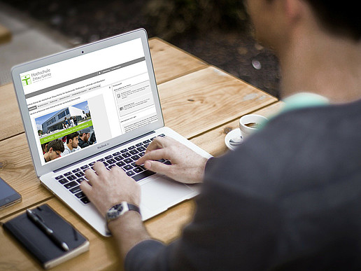 Young man at a laptop. On the screen is the university's application page.