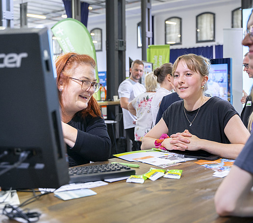 Visitors gather information from an employee at a table.