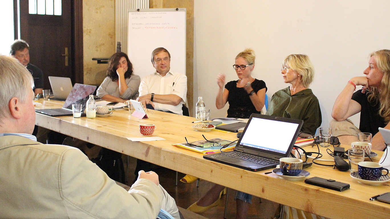 Filmschaffende und Hochschulmitarbeitende diskutieren am Tisch über ein Konzept für die anvisierte Filmakademie.