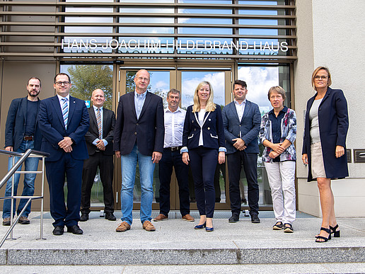 The University Council poses in front of the main entrance to the Hans-Joachim-Hildebrand-Haus.