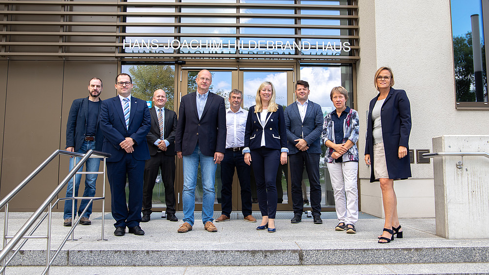 The University Council poses in front of the main entrance to the Hans-Joachim-Hildebrand-Haus.