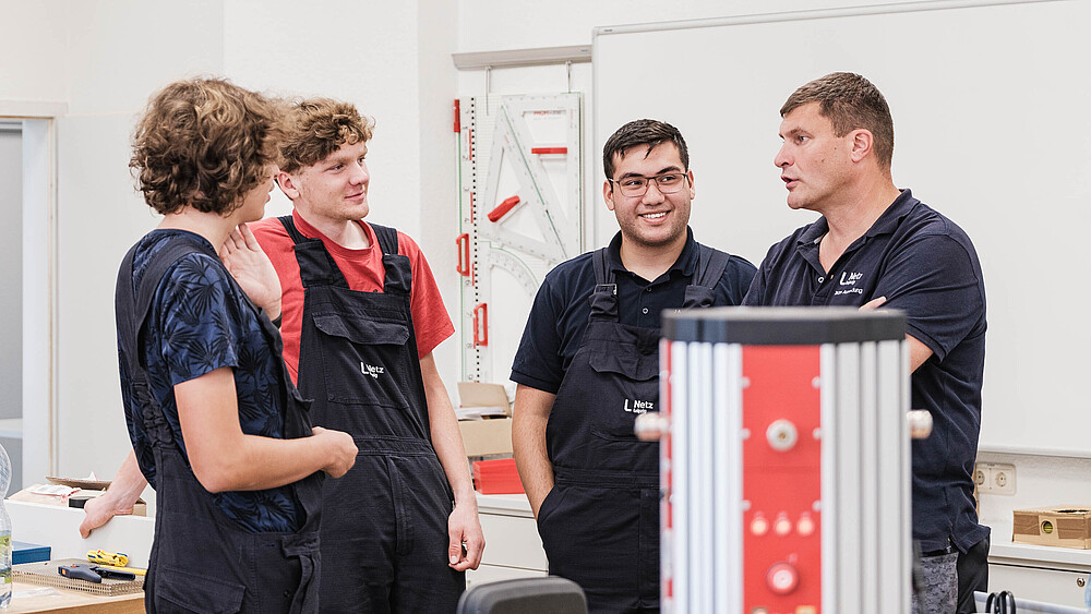 Foto: Tine Jurtz Vier KIA-Studenten und ihr Ausbilder stehen zusammen und unterhalten sich.
