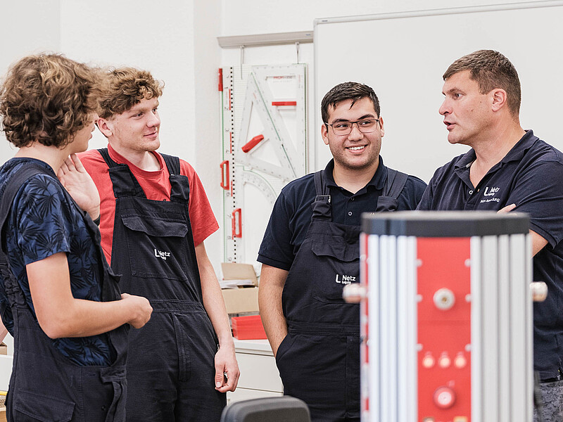 Vier KIA-Studenten und ihr Ausbilder stehen zusammen und unterhalten sich.