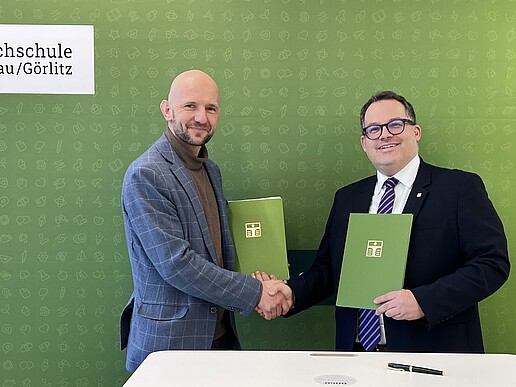 District Administrator Dr. Stephan Meyer and Rector Prof. Dr.-Ing. Alexander Kratzsch hold the signed cooperation agreements in their hands after the signing ceremony.
