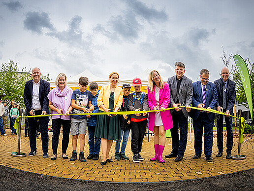 A group photo of the guests of honor as they cut the ribbon in front of the green classroom with golden scissors.