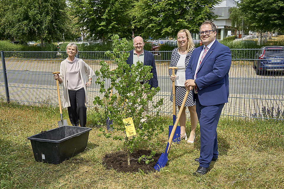 The university management stands with shovels around a planted tree.