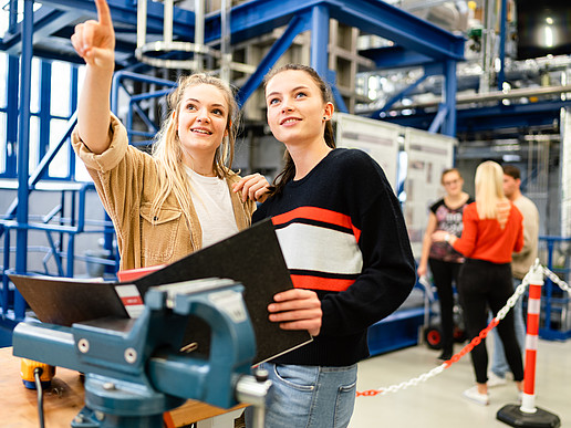 Two students are standing in the Zittau power plant laboratory. Their eyes fall in the direction one of the students is pointing.