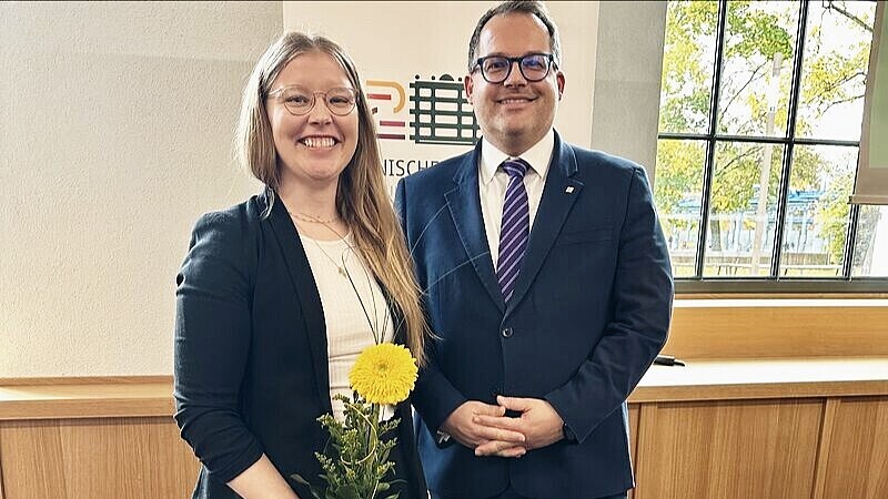 Professor Schellhammer stands next to Rector Kratzsch and holds a yellow flower in her hand, both smiling into the camera.
