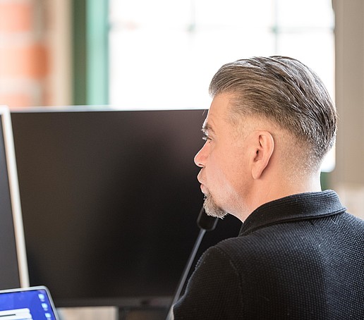 HSZG employee in front of his laptop screen in the technical room