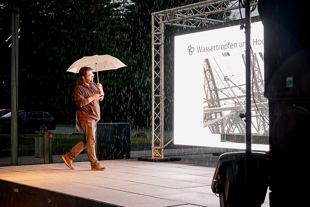 Prof. Weber on stage in front of an LED screen