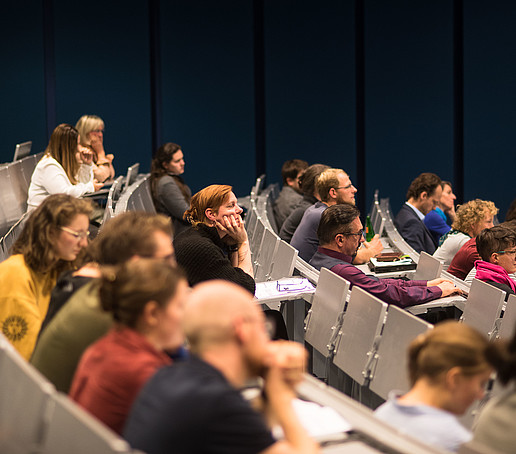 Many rows of seats in a lecture hall are occupied.