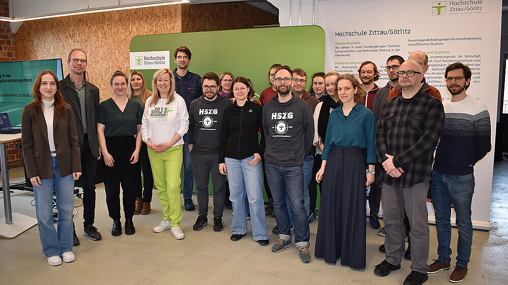 Eine Gruppe Workshopteilnehmende stehen zum Gruppenbild im Workshopraum nebeneinander.
