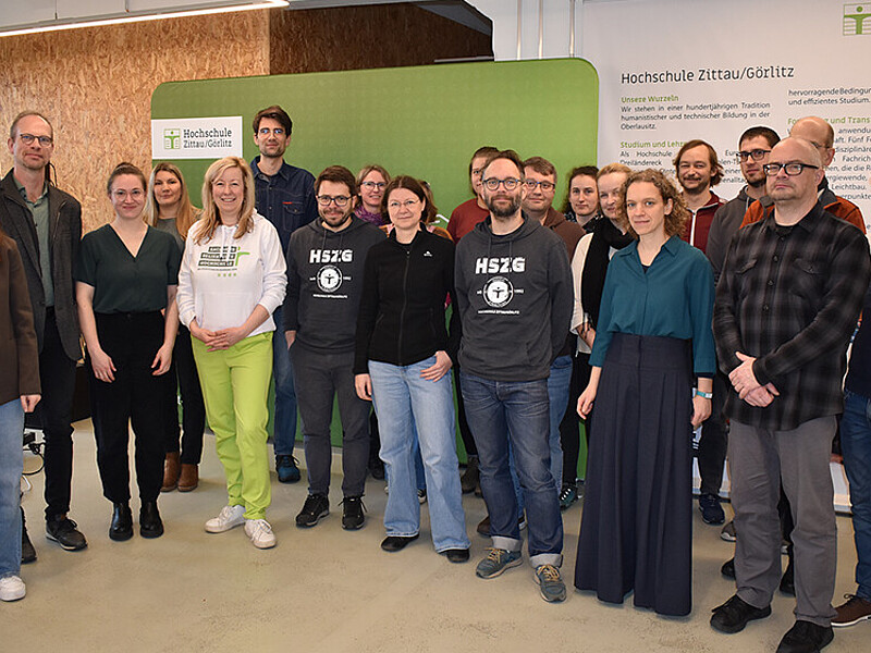 Eine Gruppe Workshopteilnehmende stehen zum Gruppenbild im Workshopraum nebeneinander.