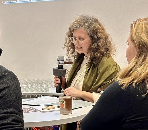 A researcher holds the microphone in her hand and delivers a pitch.