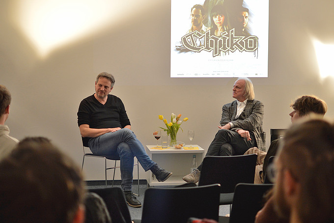 Bei einem Werkstattgespräch sitzt Bernd Hölsken mit einem Dozenten vor einem Publikum.