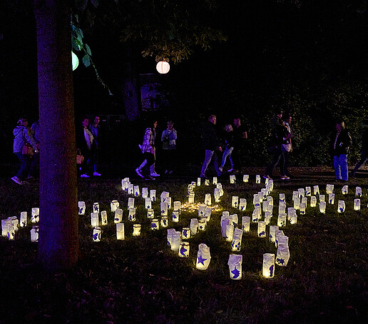 Candles in baking paper bags form the pattern of a butterfly on a meadow.