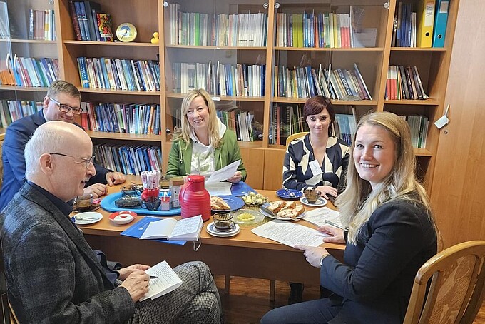 University staff sit in an office with brown wooden furniture talking to representatives from Jelenia Gora.