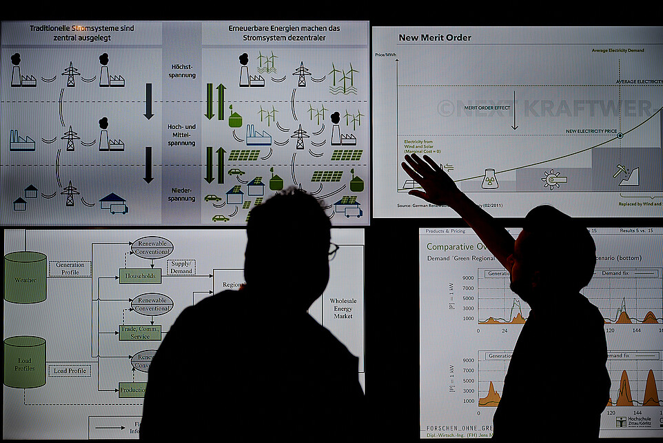 Two people are standing in front of a screen.